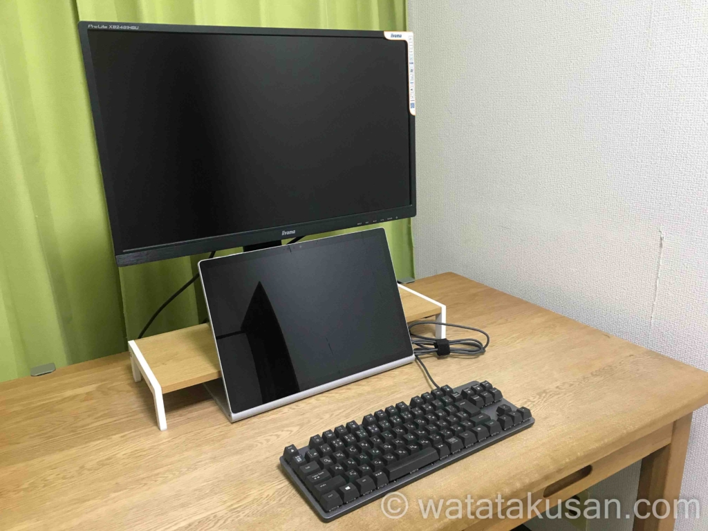 ニトリのラックヴィトの上にモニターをのせ、Surfacebook2、有線のキーボードを置いている。